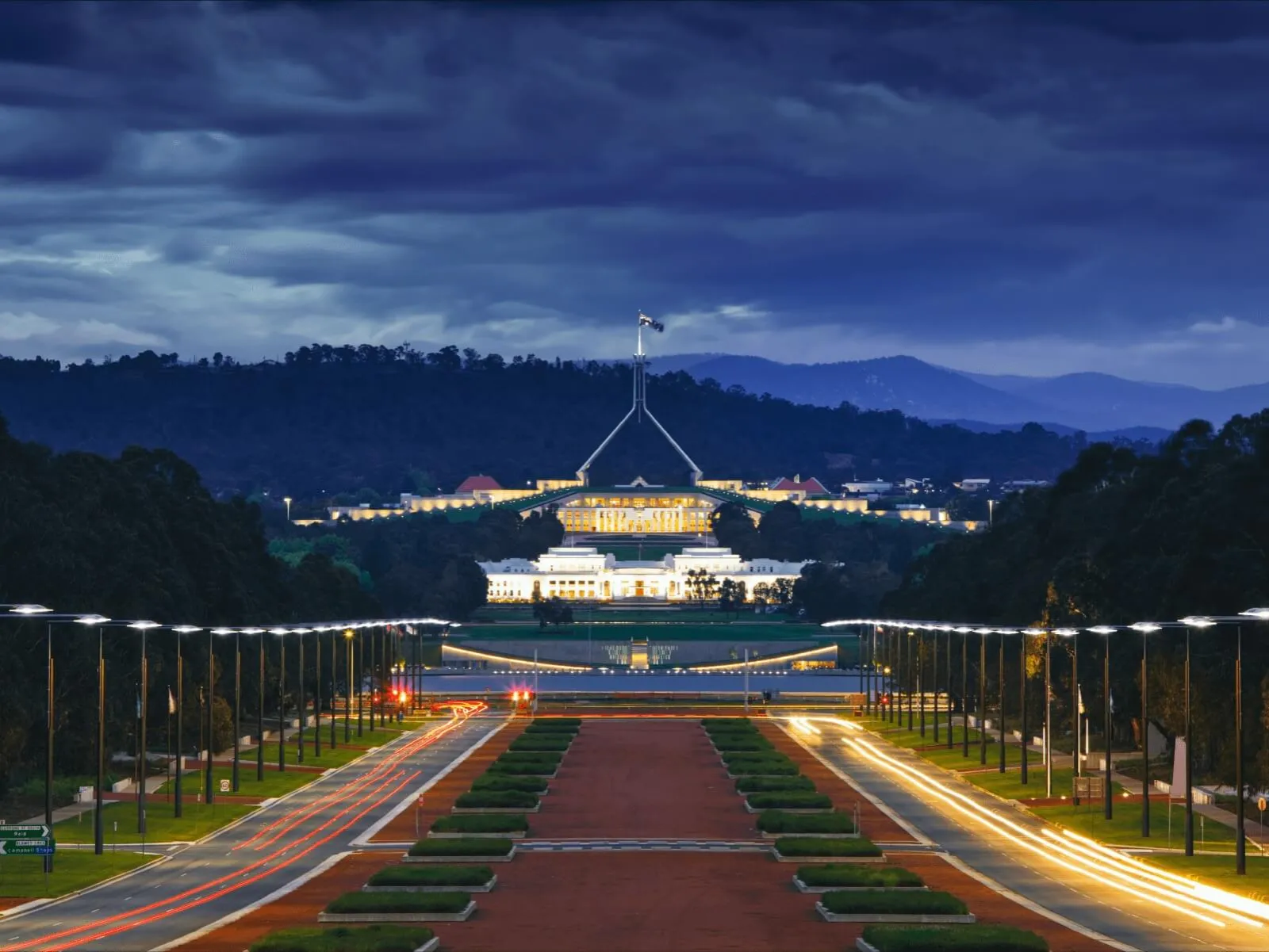 Anzac Parade at dusk, looking across the lake to Old Parliament House and Parliament House.
