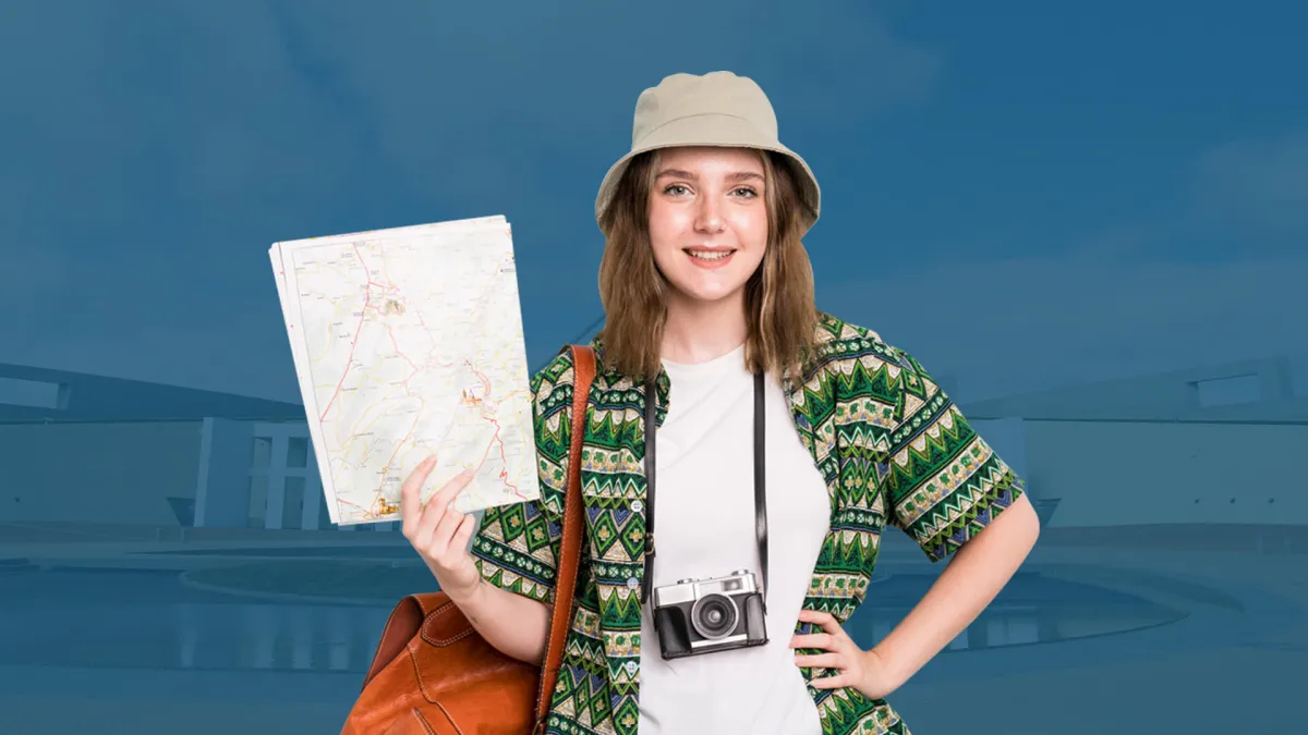 Smiling traveller in a bucket hat holding a paper map, with a camera around her neck