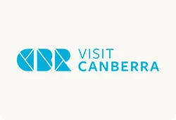Visit Canberra logo showing stylised blue geometric ‘CBR’ shapes to the left of the words ‘VISIT CANBERRA’ in blue on a pale background.