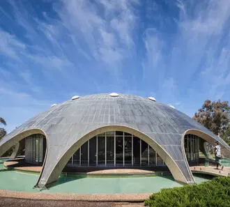 The domed Shine Dome building beside a shallow pool.