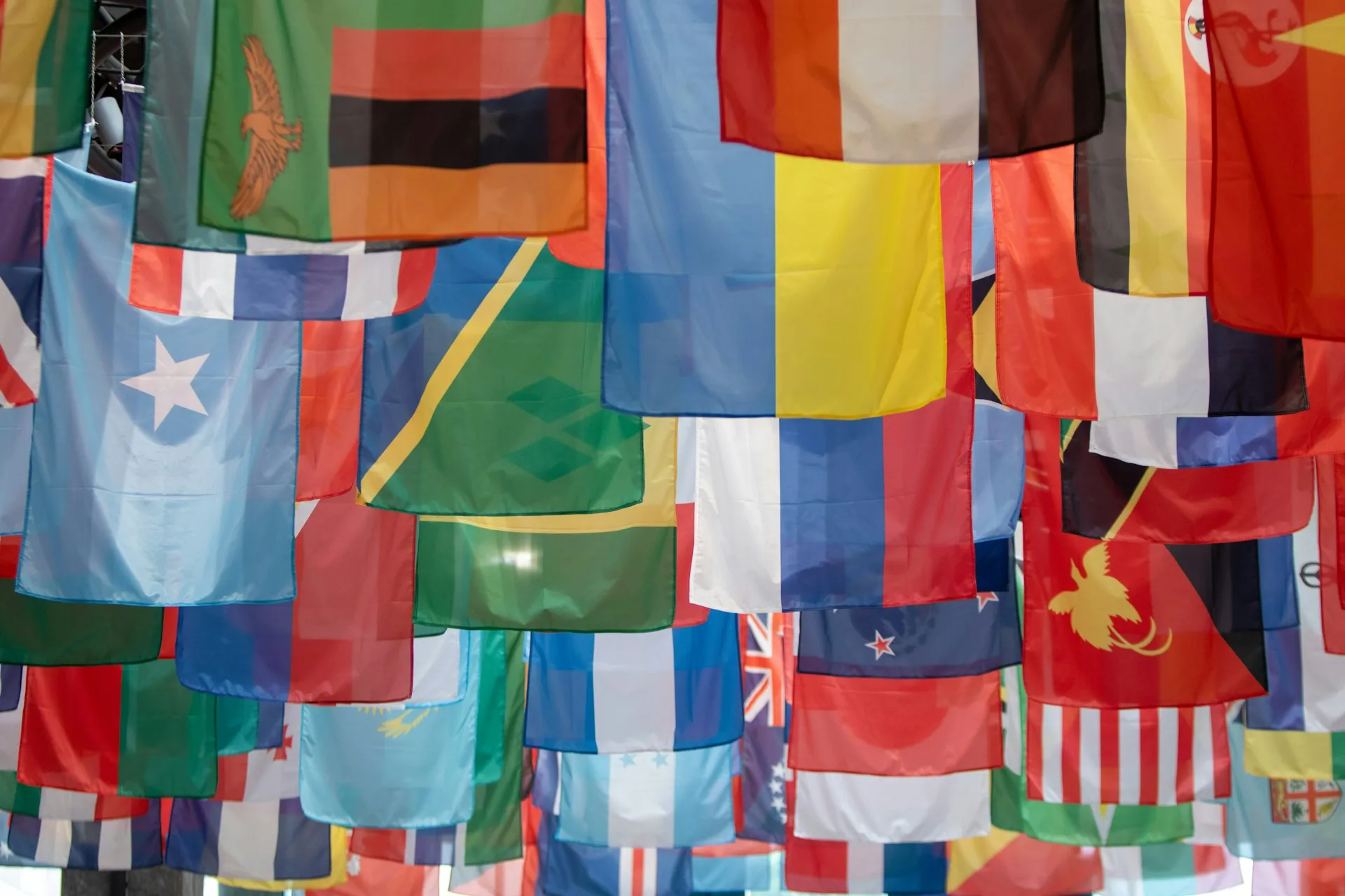 The flags of many nations hanging side by side from a ceiling.